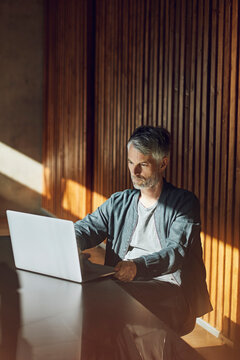 Casual businessman sitting in his sustainable office, using laptop