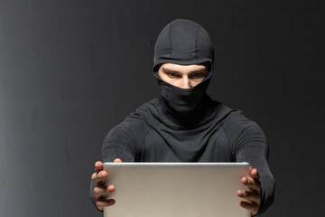 Masked hacker using laptop