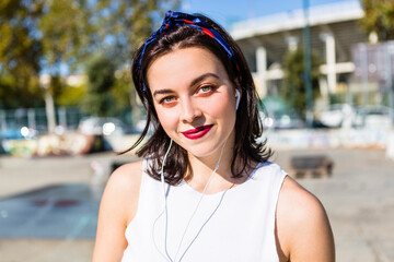 Portrait of smiling young woman with earbuds in the city