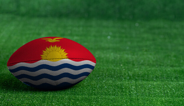 American football ball  with Kiribati flag on green grass background, close up