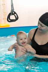 Fototapeta na wymiar Baby swimming, mother with daughter in swimming pool
