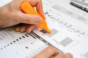 Close-up of businessman using highlighter on a report at desk in office