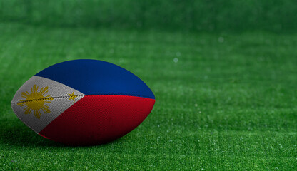 American football ball  with Philippines flag on green grass background, close up