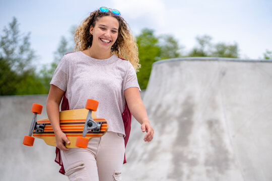 Smiling young woman with a longboard at a skatepark