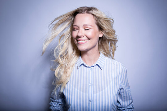 Portrait of happy blond woman tossing her hair