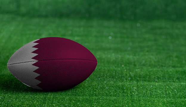American football ball  with Qatar flag on green grass background, close up