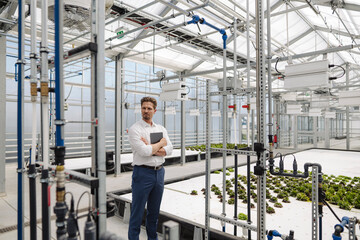 Male entrepreneur with digital tablet standing in plant nursery