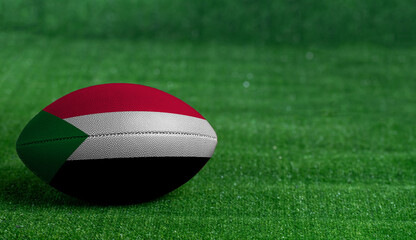 Plakat American football ball with Sudan flag on green grass background, close up
