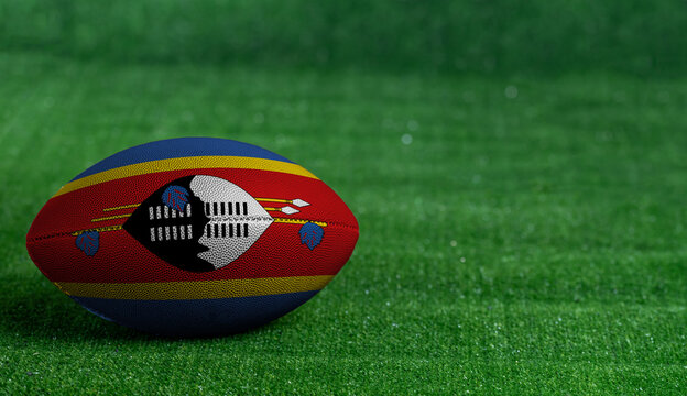 American football ball  with Swaziland flag on green grass background, close up