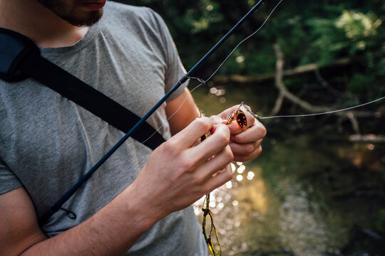 Man's hand fixing bait on fishing hook, partial view