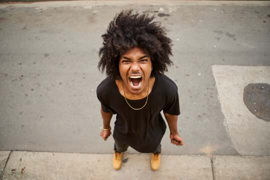 Portrait of screaming young man with afro standing on the street