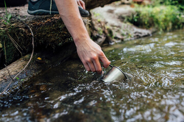 Young man's hand scooping fresh water from a brook, close-up
