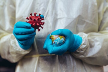 Healthcare worker holding model of Corona Virus, crushing a mini globe