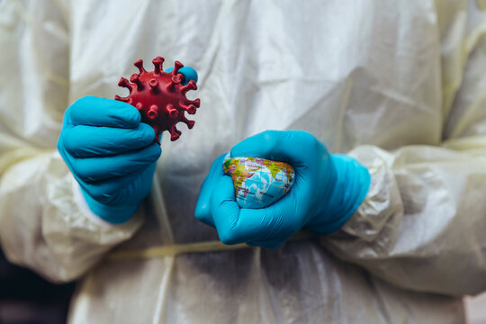 Healthcare worker holding model of Corona Virus, crushing a mini globe