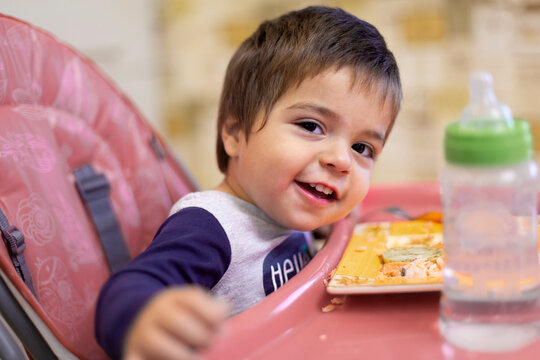 Portrait of smiling little boy sitting on high chair