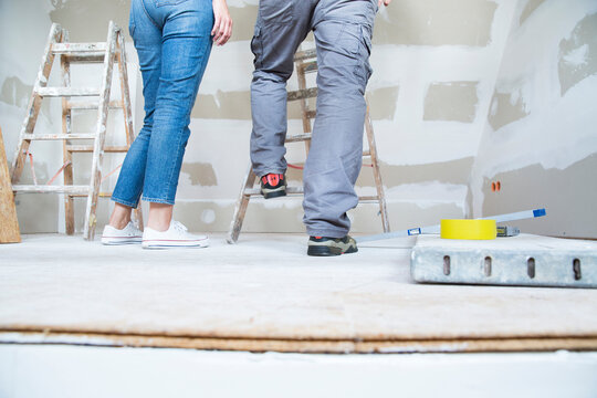 Legs of couple with ladder in attic to be renovated