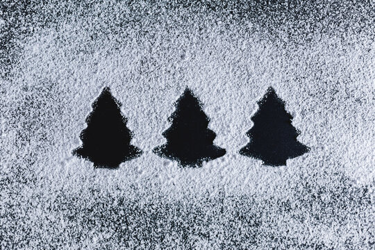 Icing sugar on black background, fir trees