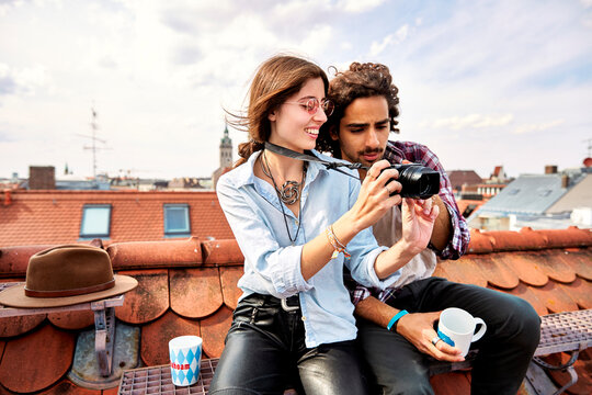 Young couple sitting on rooftop and taking pictures