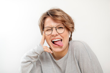 Portrait of young woman with wireless earphones pulling funny faces