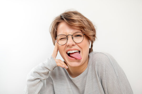 Portrait of young woman with wireless earphones pulling funny faces