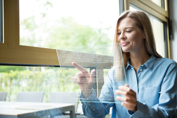 Businesswoman using futuristic tablet, glass pane