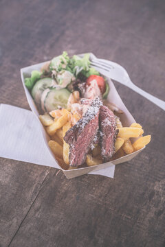 Street food, flank steak with French fries, cheese sauce and salad