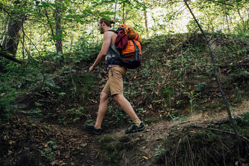 Young man with backpack hiking in a forest