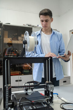 Student setting up 3D printer, using laptop