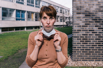 Portrait of woman taking off mask and pulling faces