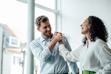 Smiling business people standing with hands clasped at cafe