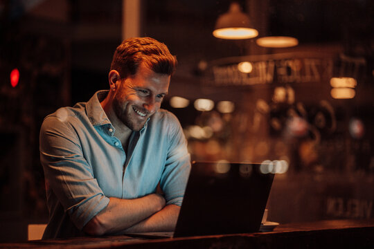 Smiling businessman using laptop while sitting at cafe