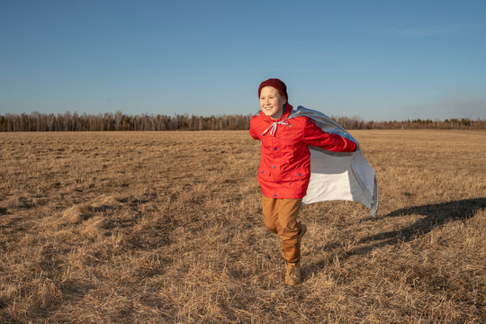 Happy boy dressed up as superhero running in steppe landscape