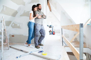 Couple in attic to be renovated looking out of window