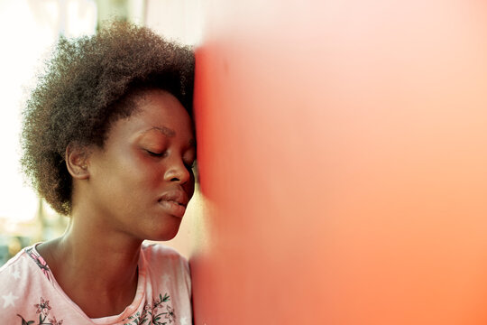 Portrait of young woman with eyes closed leaning flagainst wall
