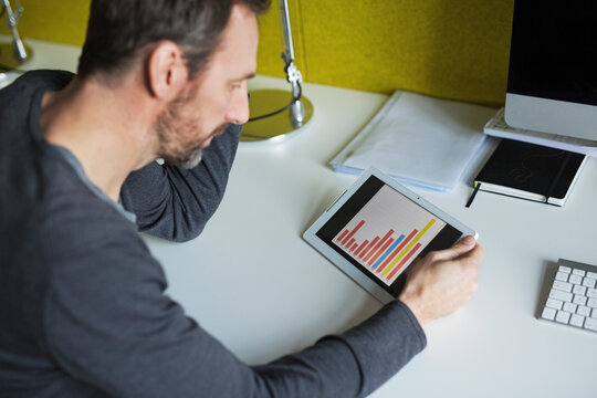 Businessman analyzing bar chart on tablet in office