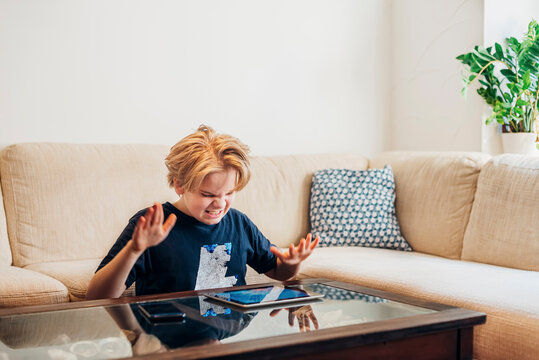 Frustrated boy with smartphone and tablet in living room