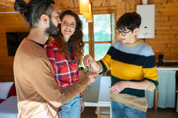 Host welcoming young couple in a cabin in the countryside handing over house key