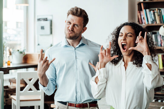 Business people gesturing hand signs while standing at cafe