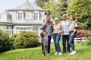 Happy extended family standing in garden of their home