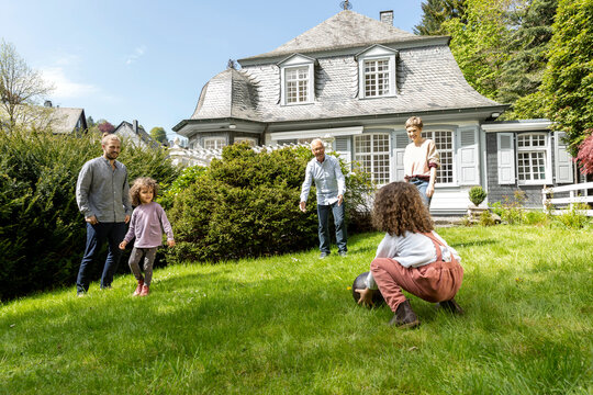 Happy extended family playing football in garden - Powered by Adobe