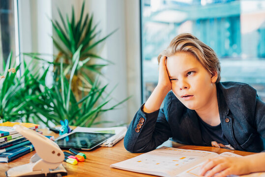 Frustrated boy sitting at desk with workbook