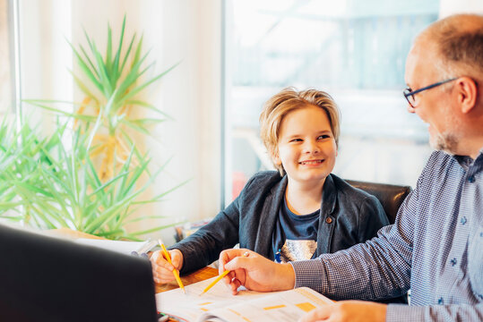 Father helping son doing homework at desk