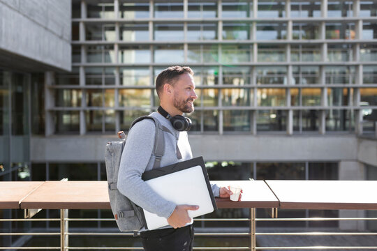 Smiling mature male professional holding files while standing against building