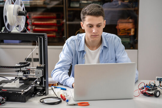 Student setting up 3D printer, using laptop