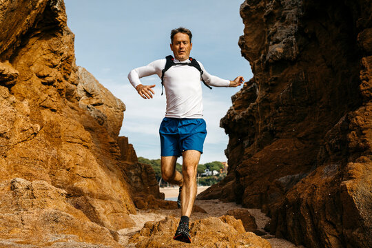 Man jumping over rocks against blue sky