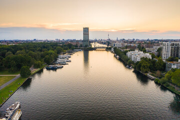 Spree river flowing amidst residential building seen from Treptower Park against sky during sunset
