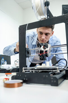 Student setting up 3D printer, using laptop