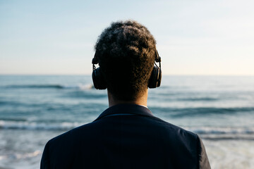 Afro man with headphones at beach