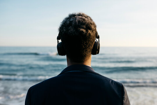 Afro man with headphones at beach