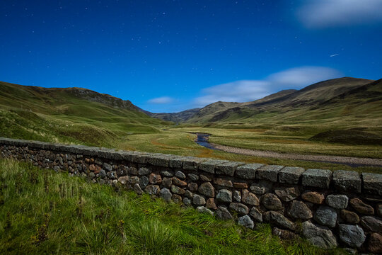 UK, Scotland, Glenshee, landscape with stone wall under starry sky